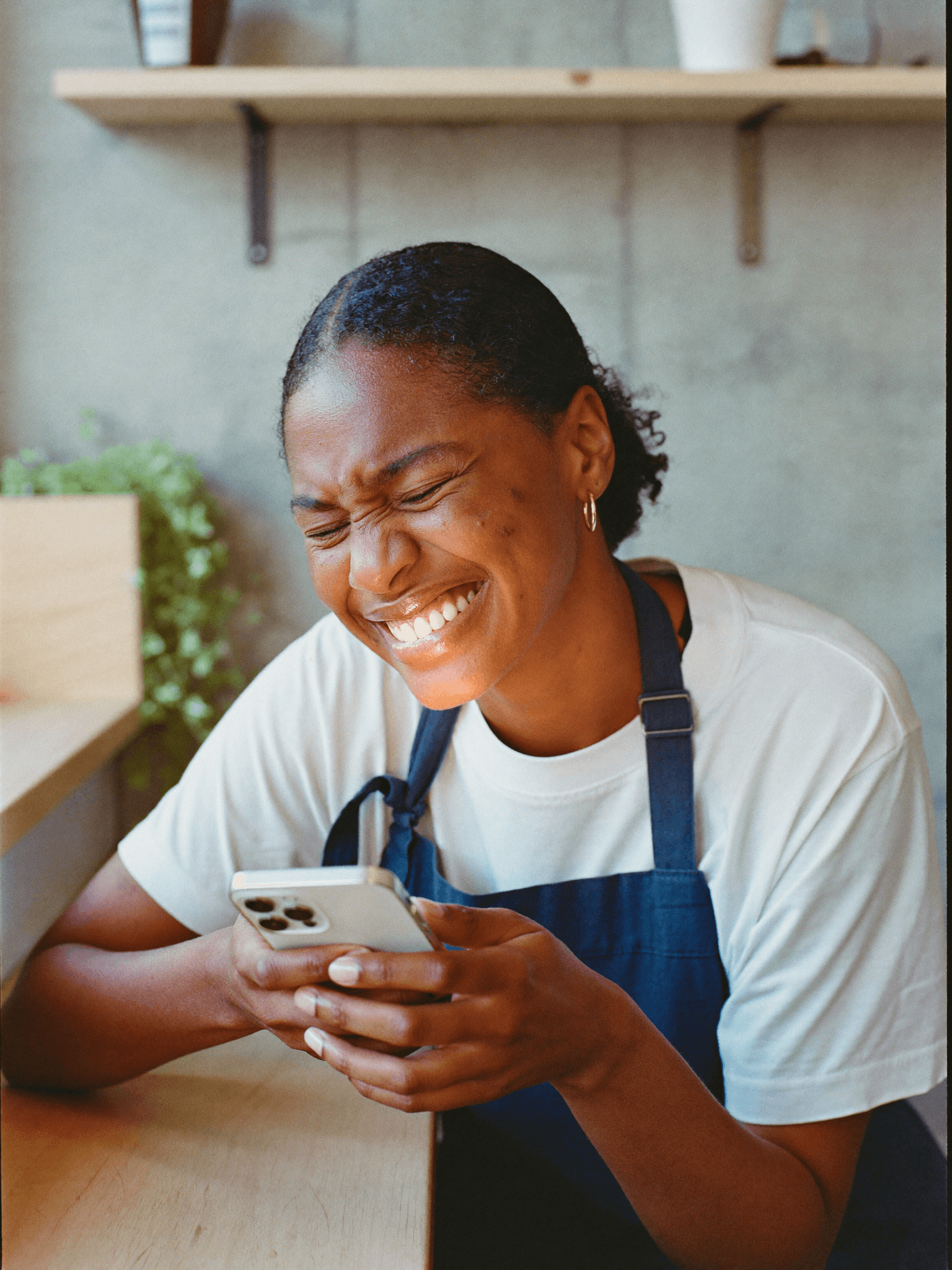 Dona de hamburgueria rindo ao abrir no celular a arte pronta que acabou de receber